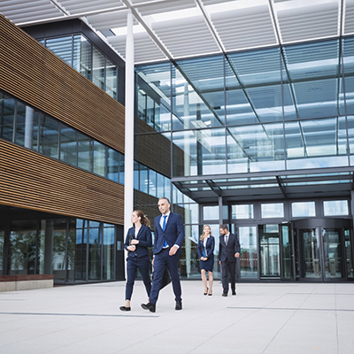 Group of business people walking outside the entrance of an office building